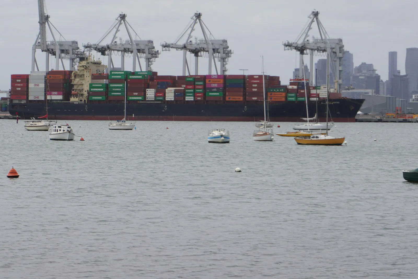 Loaded container ship at the Port of Melbourne under gantry cranes, seen across the water from Williamstown