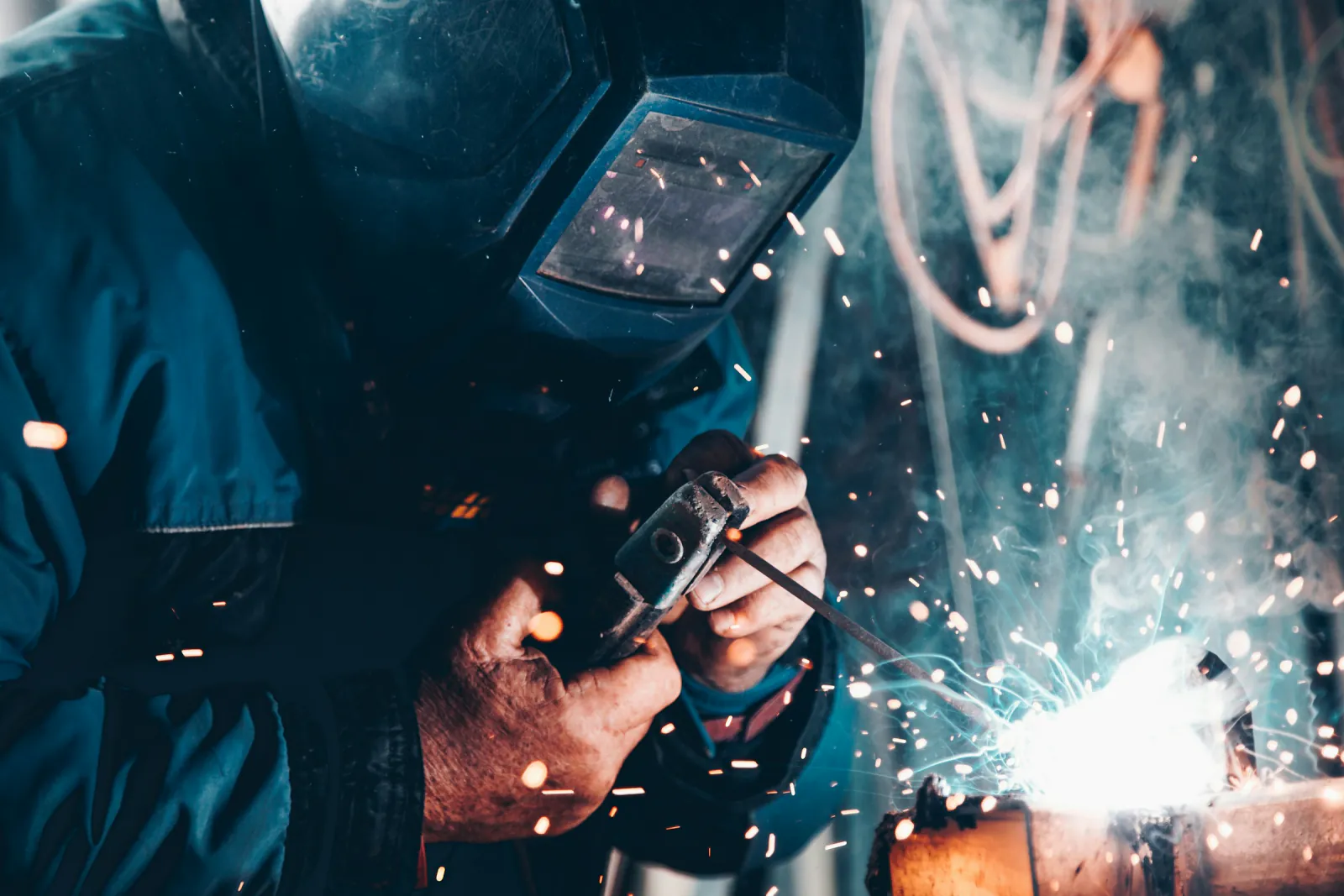Welder in a protective helmet joining steel as sparks fly, Hay, New South Wales